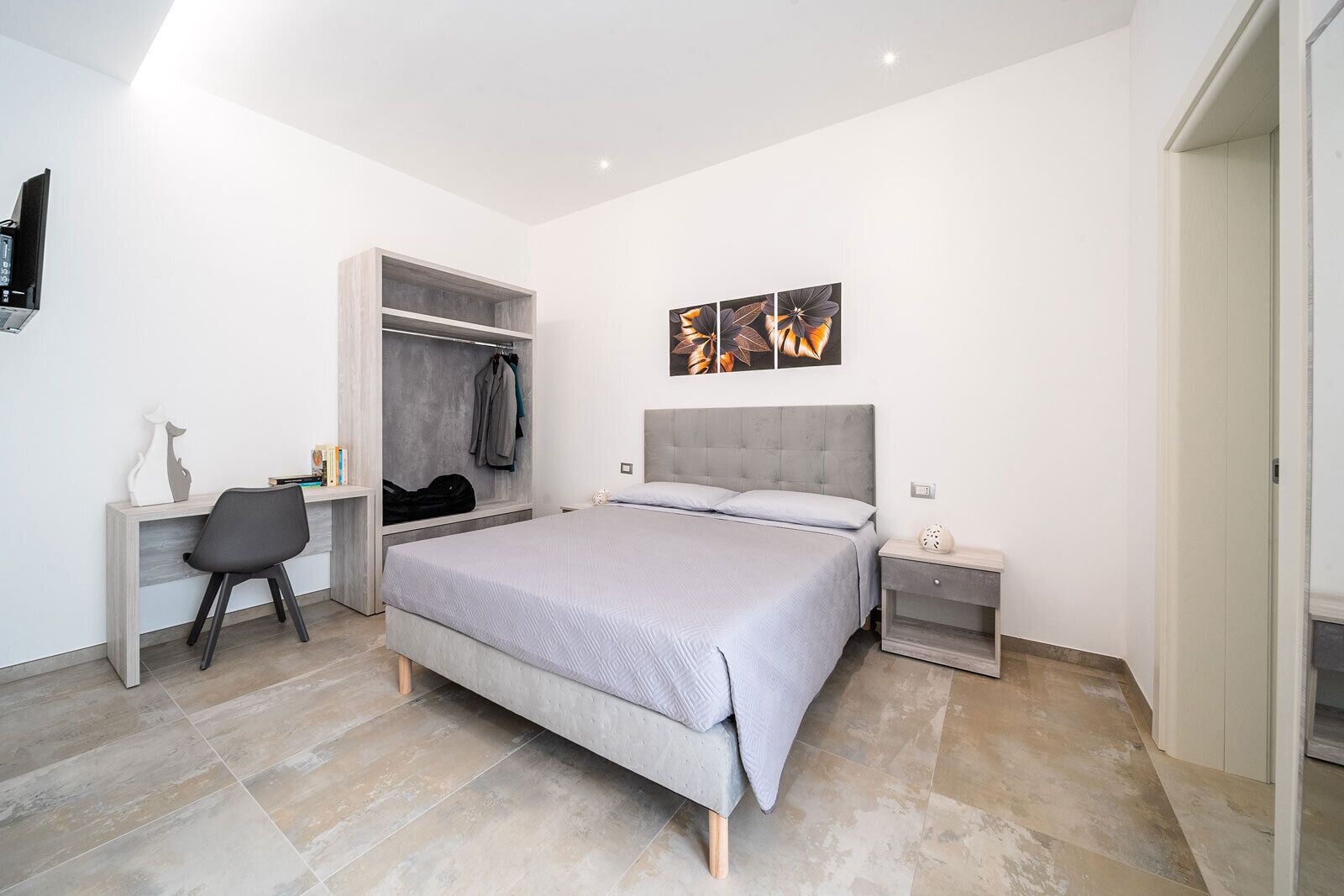 A modern bedroom with a bed, a desk, and a wardrobe.