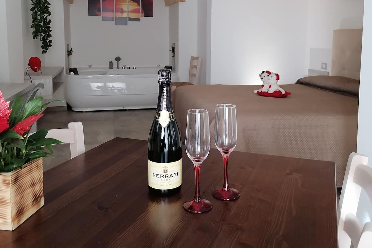 A dining area with a wooden table, a bottle of wine, and two wine glasses.