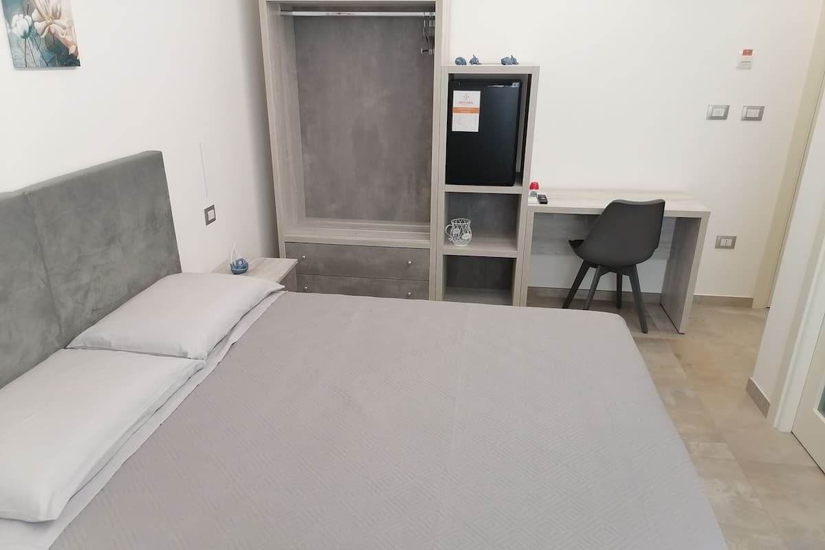 A bedroom with a bed, a desk, and a chair.