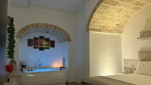 Quarto moderno com uma grande janela em arco, uma banheira e uma cama.