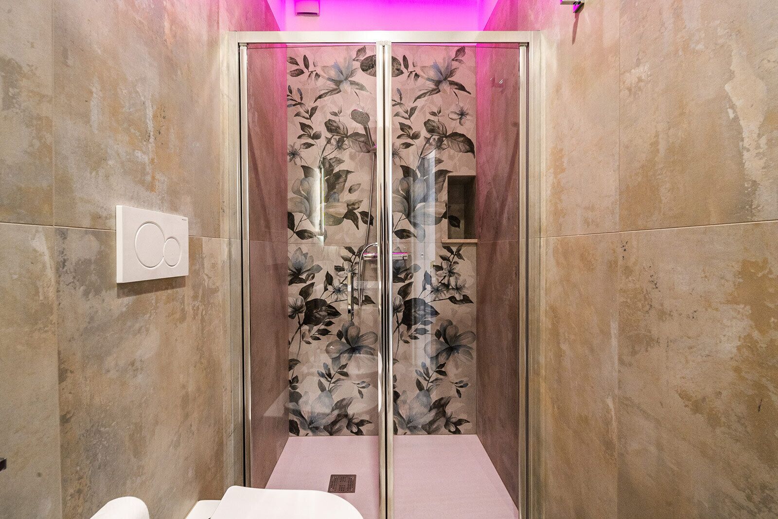 A bathroom with a glass shower enclosure, a toilet, and a sink.