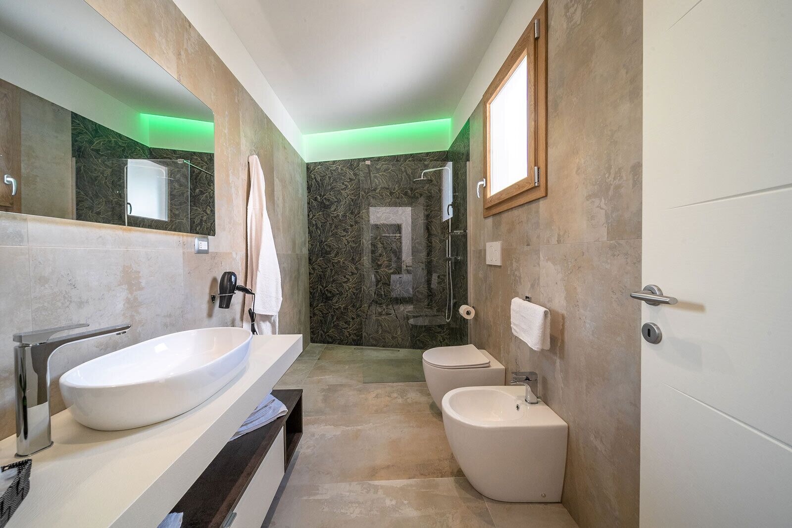 A modern bathroom with a large white sink, a bidet, and a toilet.