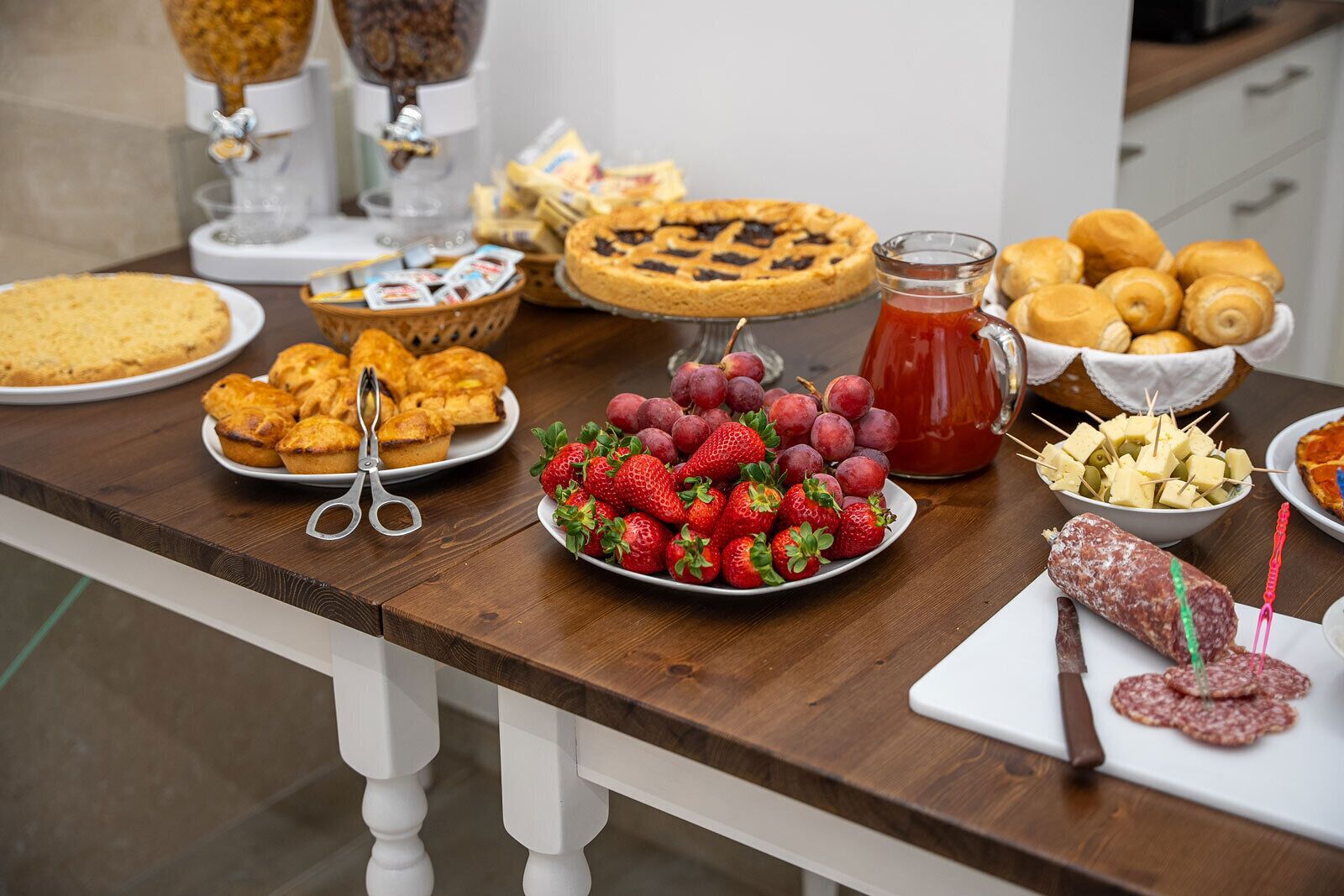 A table with various food items including pastries, a pie, strawberries, and cheese cubes.