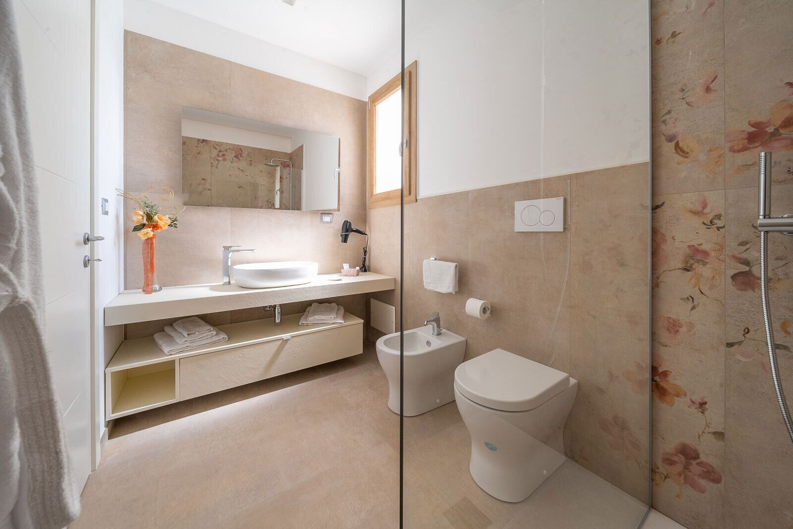 A modern bathroom with a large mirror, a sink, a toilet, and a shower.