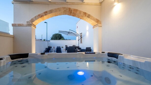 Uma área de banheira de hidromassagem com assentos e uma pérgola acima.