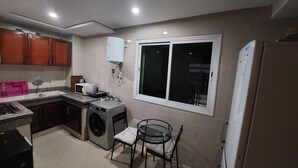 A compact kitchen with a washing machine, a microwave, and a sink. - Appartement Centre-ville (Kénitra)