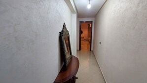 A narrow hallway with a wooden bench and a decorative mirror on the wall. - Appartement Centre-ville (Kénitra)