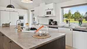 A modern kitchen with white cabinets, a large island, and a view of the outdoors. - Gorgeous home in Rømø with sauna (Rømø)