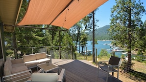 A deck with outdoor furniture, a canopy, and a view of a lake with boats.