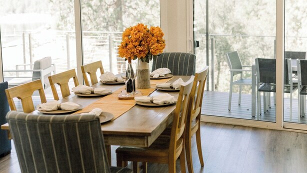 A dining area with a wooden table, striped chairs, and a vase of flowers.