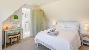 Un dormitorio con cama, mesitas de noche, un escritorio y un espejo.