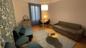 Una sala de estar con un sofá, un sillón adicional, una mesa de centro y una zona de comedor con una mesa y sillas.