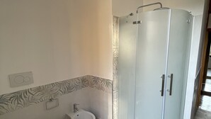 Un baño con inodoro, bidé y ducha a ras de suelo.