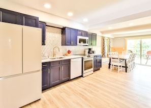 A modern kitchen with dark cabinets, a white refrigerator, a microwave, and a stove. - Best Mountain Views Triple level Deck /w Hot tub facing mountains!! (Tannersville)