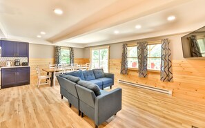 A modern interior with a grey sectional sofa, wooden flooring, and a dining area with white chairs. - Best Mountain Views Triple level Deck /w Hot tub facing mountains!! (Tannersville)