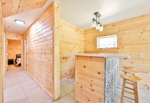 A wooden interior with a kitchen area, including a counter and stools, and a door leading to another room. - Best Mountain Views Triple level Deck /w Hot tub facing mountains!! (Tannersville)