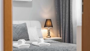Un dormitorio moderno con una cama bien hecha, una lámpara de noche y una pequeña estantería con un objeto decorativo.