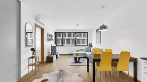 Una sala de estar moderna con comedor, ventanas grandes y vistas a la ciudad.
