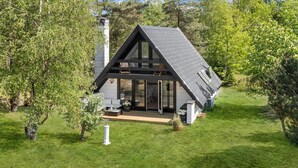 A modern house with a sloped roof, large windows, and a patio area.