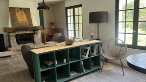 Una sala de estar acogedora con chimenea, una estantería verde y un ventanal grande.