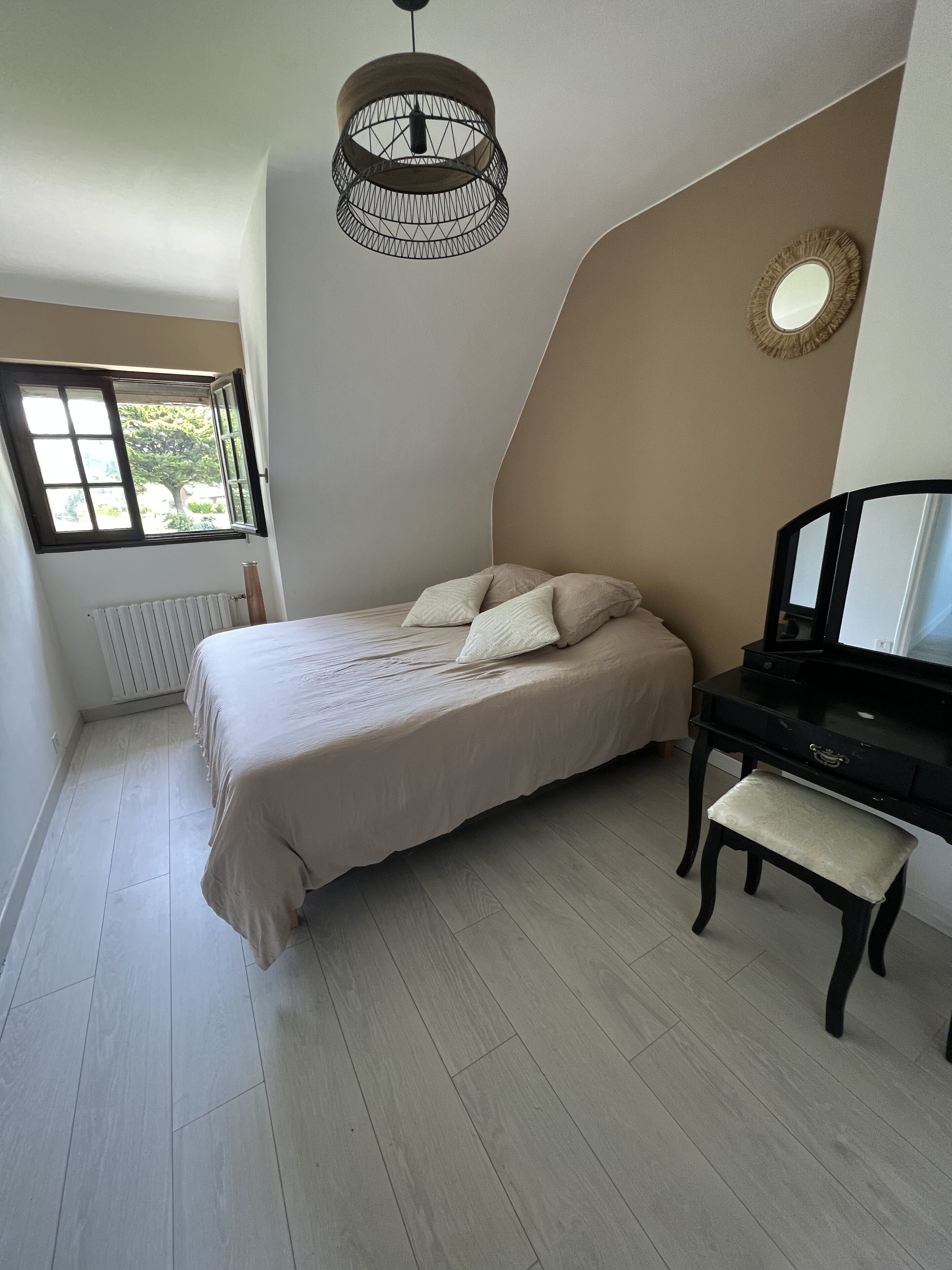 Une chambre à coucher comprenant un lit, un bureau, une chaise, un radiateur, une fenêtre et un luminaire au plafond.