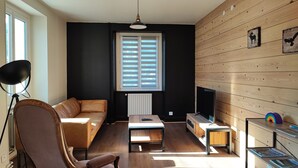 Una sala de estar moderna con sofá, mesa de centro y televisor.