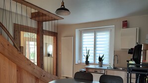Una cocina moderna con comedor, escalera de madera y ventana con persianas.