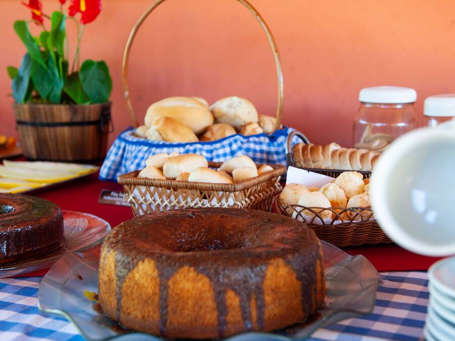 Un tavolo da buffet con diversi prodotti da forno, tra cui una torta bundt e cestini di pane.