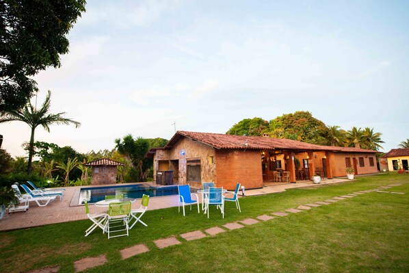 A house with a swimming pool, outdoor seating, and a well-maintained lawn. - SITIO TOCA DO LEAO (Guarapari)