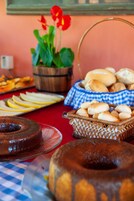 Una mesa de buffet con diversos productos horneados, incluyendo un pastel y panecillos, además de una cesta con manzanas en rodajas.