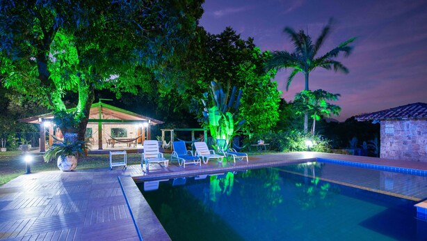 Une piscine avec des chaises longues, un espace de détente couvert et une végétation luxuriante.
