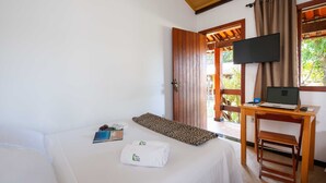 Une chambre d’hôtel avec un lit, un bureau avec un ordinateur portable, une télévision et une fenêtre avec des rideaux.