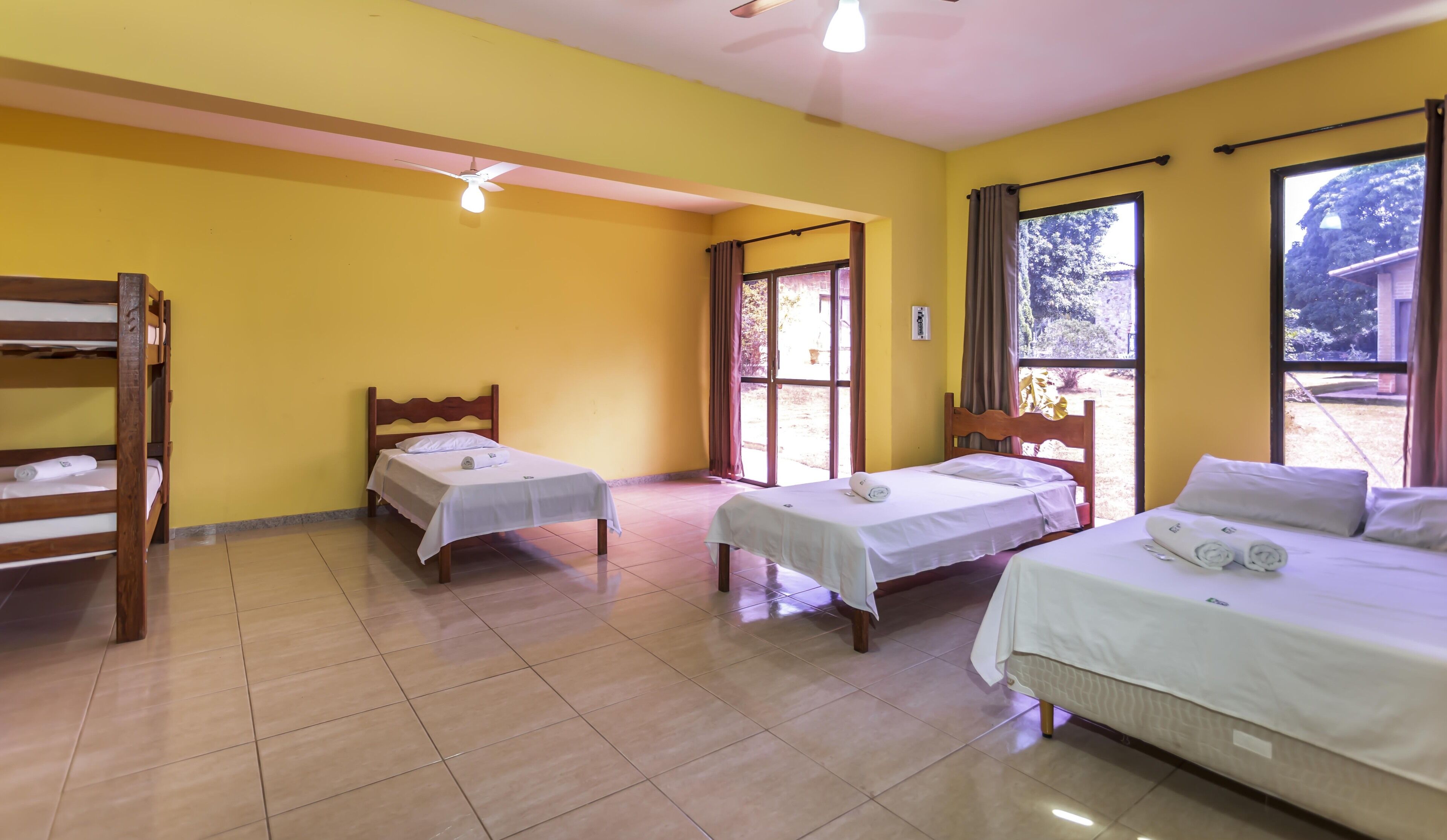 A room with two single beds, a bunk bed, and a ceiling fan.