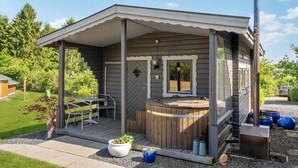 A small cabin with a hot tub, outdoor seating, and a deck.