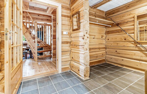 A wooden cabin interior with a staircase leading to a balcony, tiled flooring, and a wooden door. - Beautiful home in Dalholen with sauna (Dalholen)