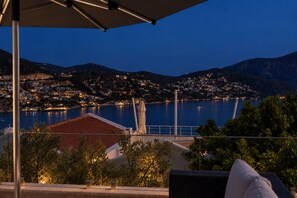A coastal view with a balcony overlooking a bay, a mountain in the background, and a building with a red roof. - Kalkan Town Centre Villa with walking distance to Old town and Harbor (Antalya)