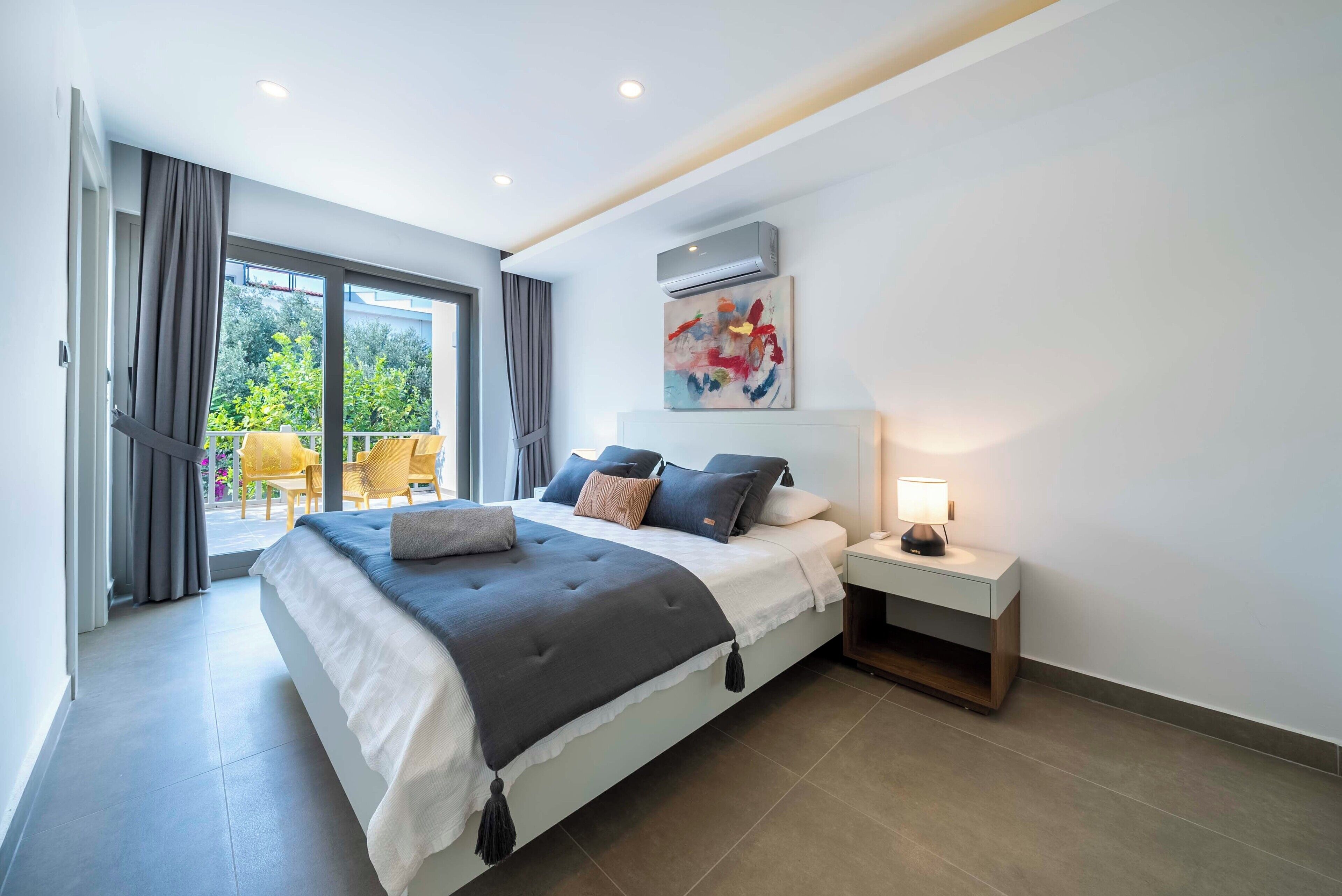 A modern bedroom with a large bed, a nightstand, and a window with curtains.