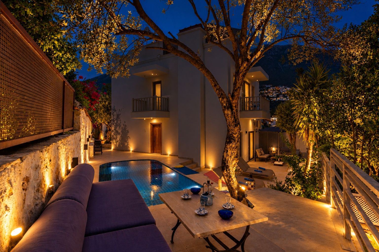 Zona de piscina con una silla de descanso, una mesa con cuencos y un árbol.