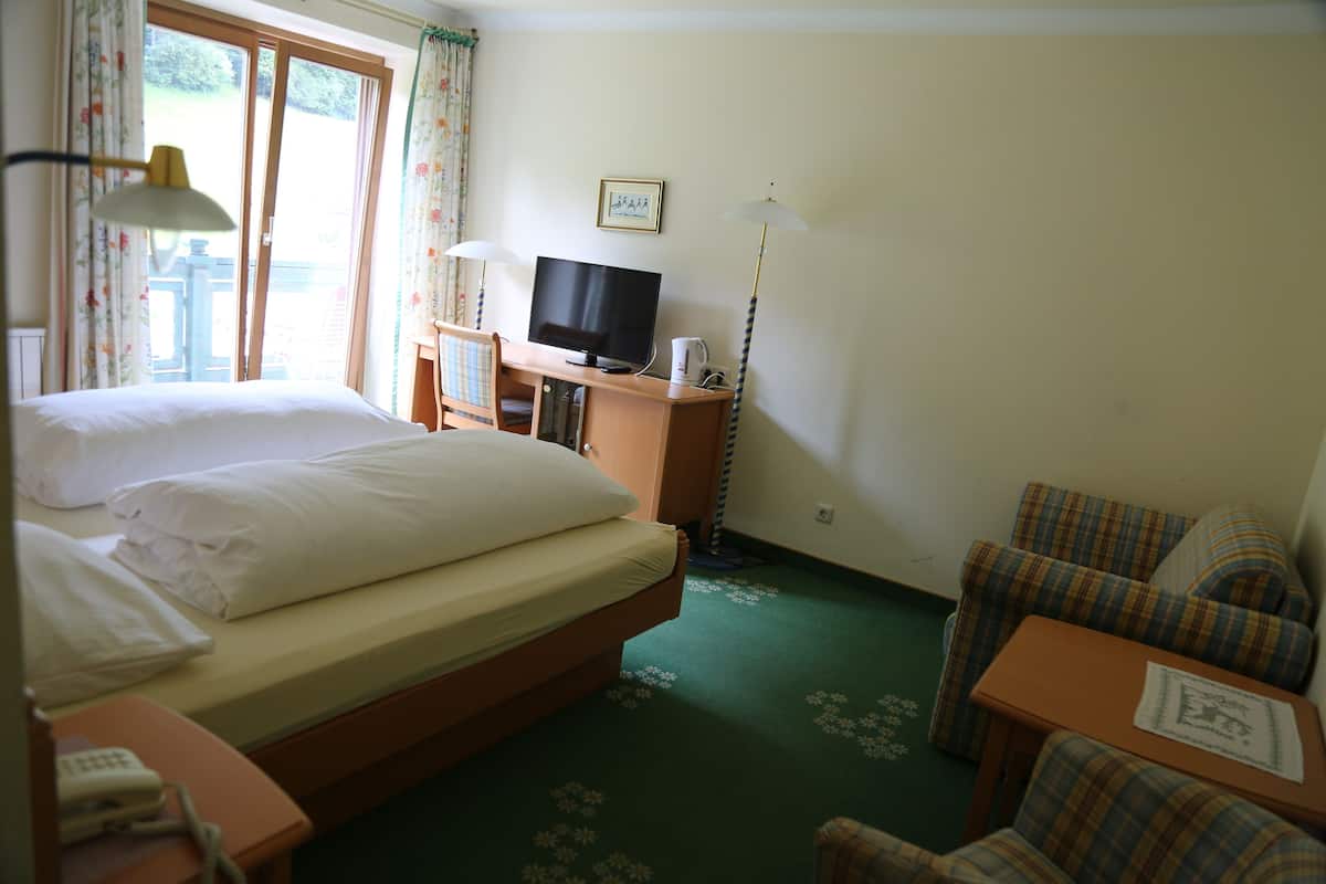 Ett hotellrum med en säng, ett skrivbord med en tv, en stol och ett litet bord.