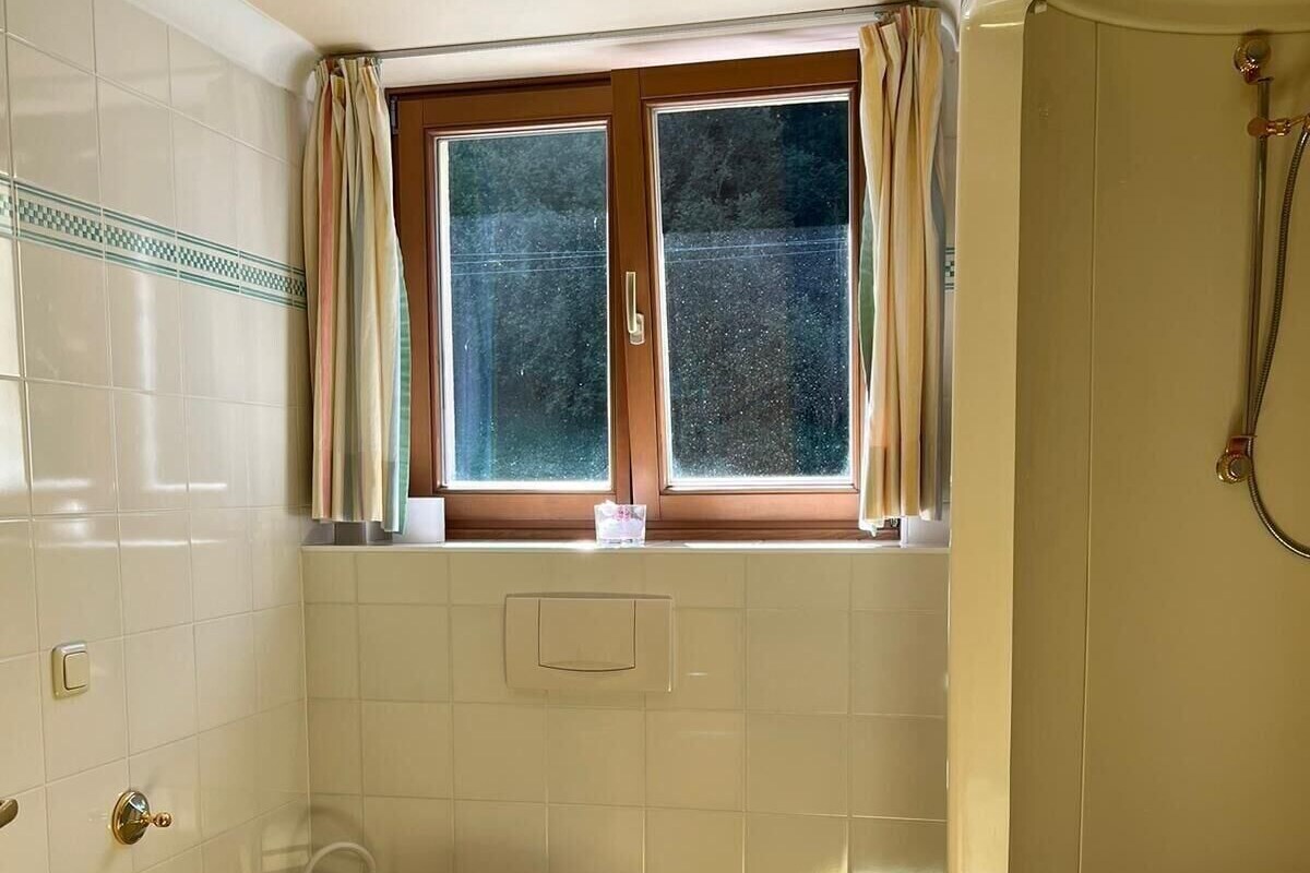 A bathroom with a toilet, a window, and a bathtub.
