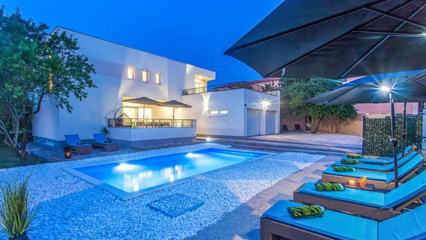 Ein Poolbereich im modernen Stil mit rechteckigem Pool, Liegestühlen und Sonnenschirmen.