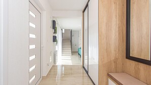 Ein moderner Korridor mit Marmorboden, einer Holzbank und einer Treppe, die in einen anderen Raum führt.