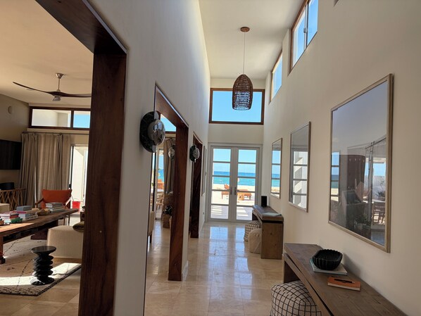 Ein geräumiger Flur mit Blick auf den Strand, Holzmöbel und Deckenventilator.