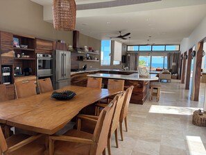 A modern kitchen with a large island, wooden chairs, and a dining table. - Beautiful Beach front Villa (La Ribera, Baja California Sur, Mexico)