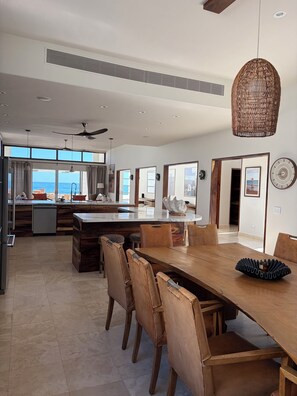 A spacious kitchen with a large island, wooden dining table, and chairs. - Beautiful Beach front Villa (La Ribera, Baja California Sur, Mexico)