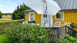 A yellow house with a white door, a porch with white chairs, and a white umbrella. - Amazing home in Västra Karup with WiFi (Västra Karup)