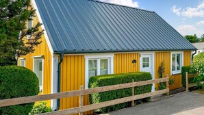 A yellow building with a blue roof, white doors, and a wooden fence. - Amazing home in Västra Karup with WiFi (Västra Karup)
