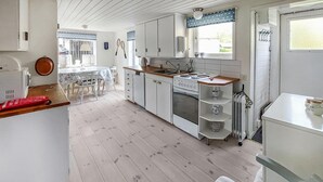 A kitchen with white cabinets, a wooden countertop, a stove, and a dining area with a table and chairs. - Amazing home in Västra Karup with WiFi (Västra Karup)