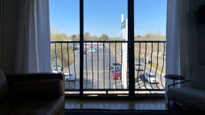Ein Zimmer mit großem Fenster mit Blick auf einen Parkplatz und ein Gebäude mit einer Fahnenstange.