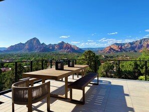 A terrace with a table and chairs, overlooking a mountainous landscape.